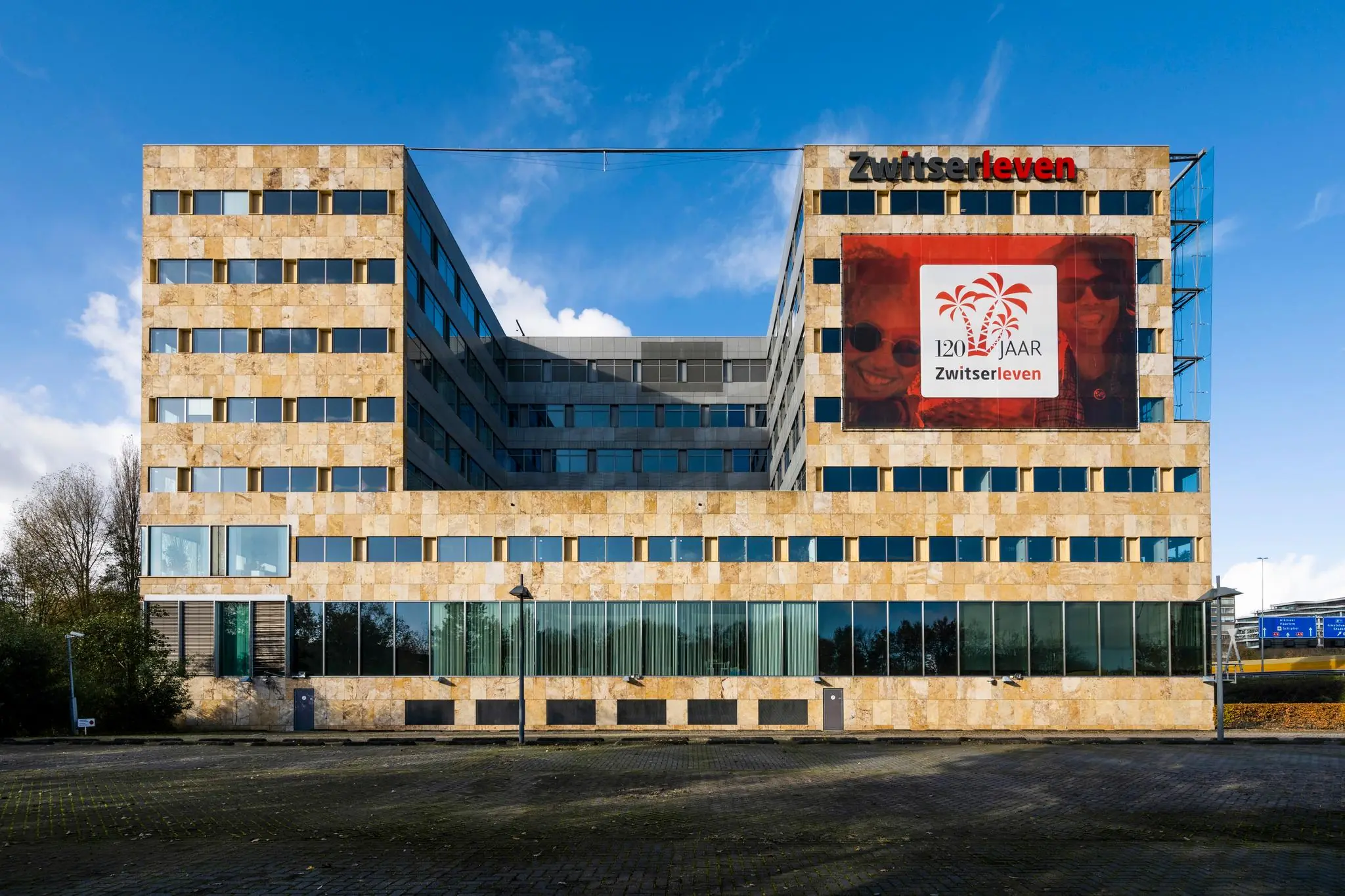Kantoorgebouw van Zwitserleven aan de Burgemeester Rijnderslaan met groot jubileumbanner op de gevel.